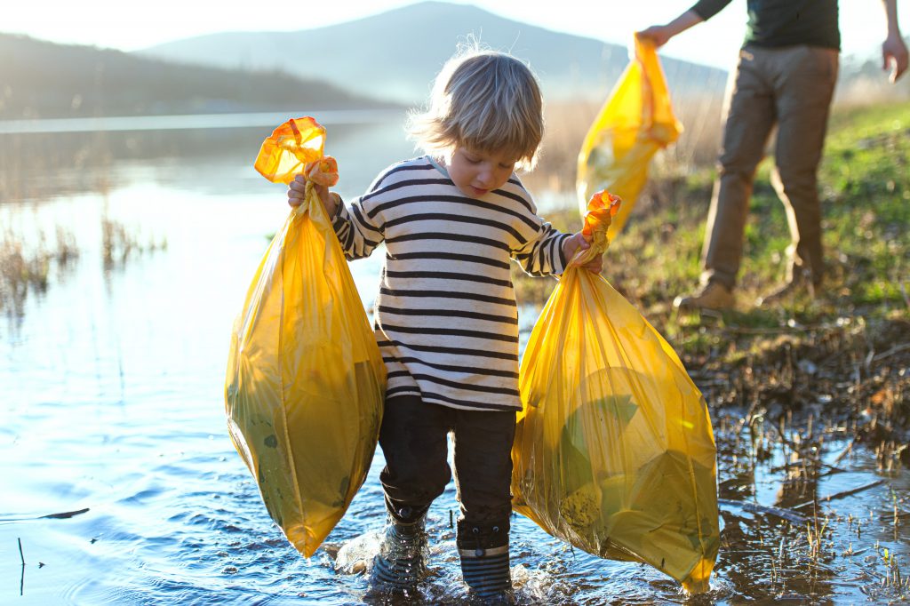 boy in wellies collecting rubbish from a river